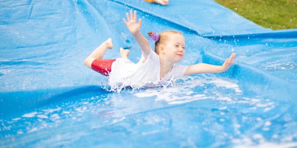 Children having fun at an Educamps Summer Camp on the slip and slide / taking part in water activities