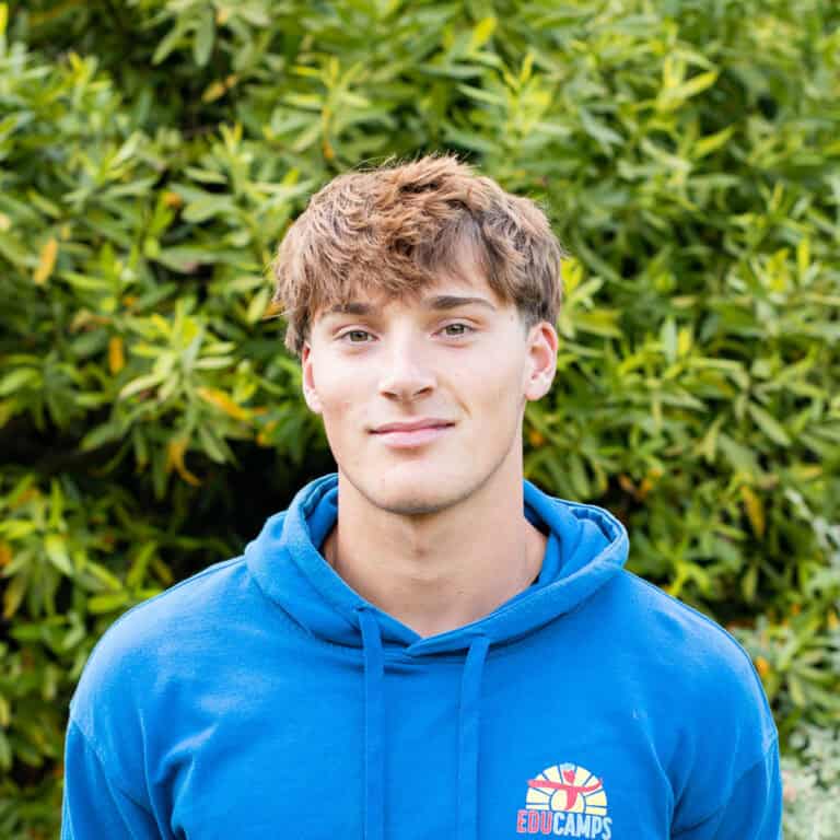 Educamps day camp leader wearing a blue Educamps hoodie, smiling outdoors and supporting children’s summer activities in nature.