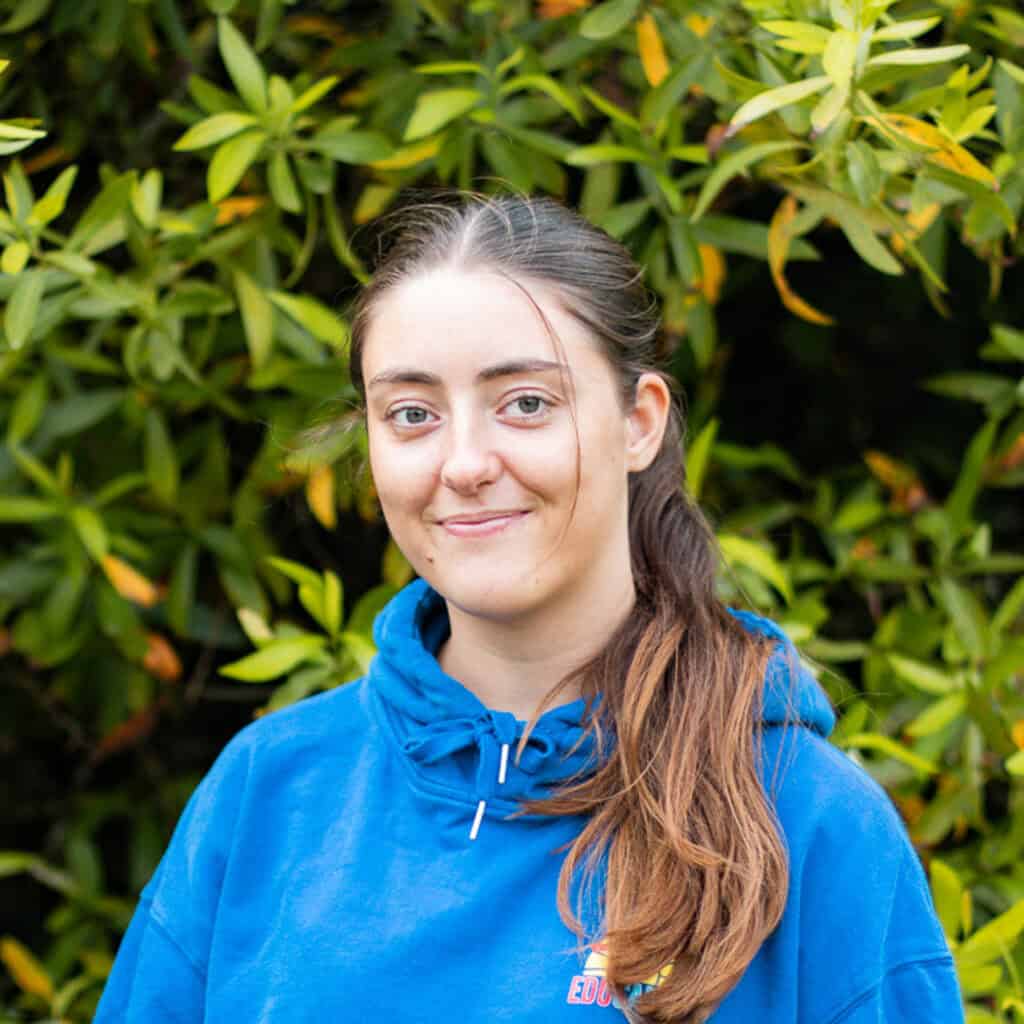 Educamps day camp leader wearing a blue Educamps hoodie, smiling outdoors and supporting children’s summer activities in nature.